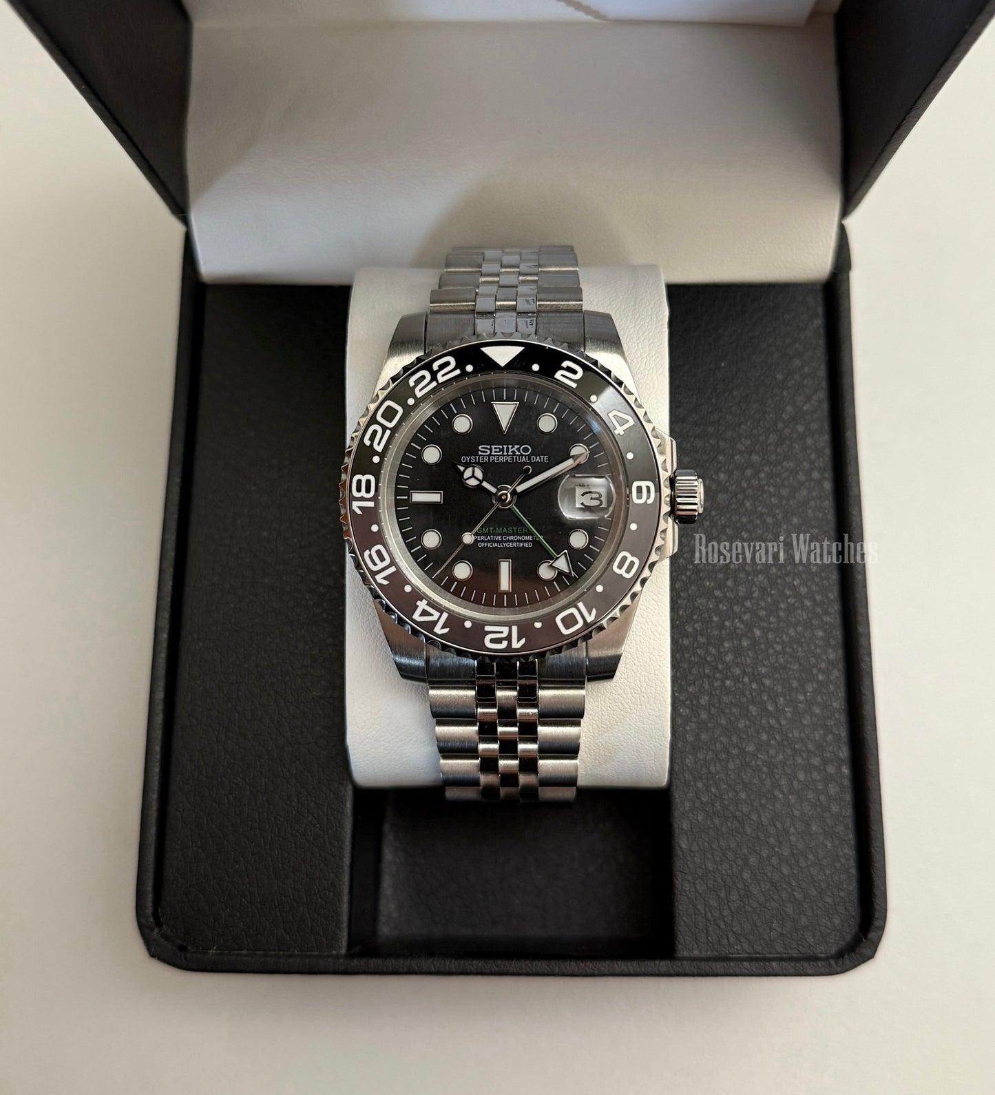 GMT (Bruce Wayne) Seiko NH34 GMT automatic mod watch. A full watch shot of a black dial watch with a black bezel inside a black presentation box.